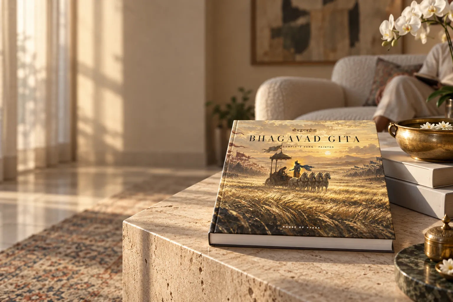 The Bhagavad Gita art book by House of Vyasa lying on a travertine coffee table in a sunlit drawing room
